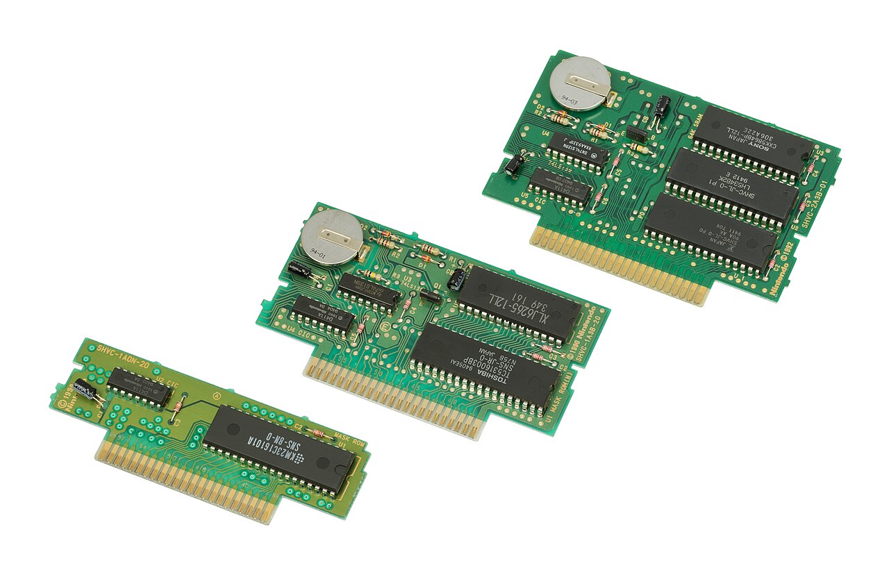 Trois circuits imprimés de cartouches Super Nintendo avec connecteurs dorés et puces, sur fond blanc.